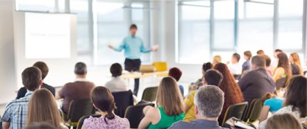Aula de formación con varias personas escuchando la explicación de un ponente.