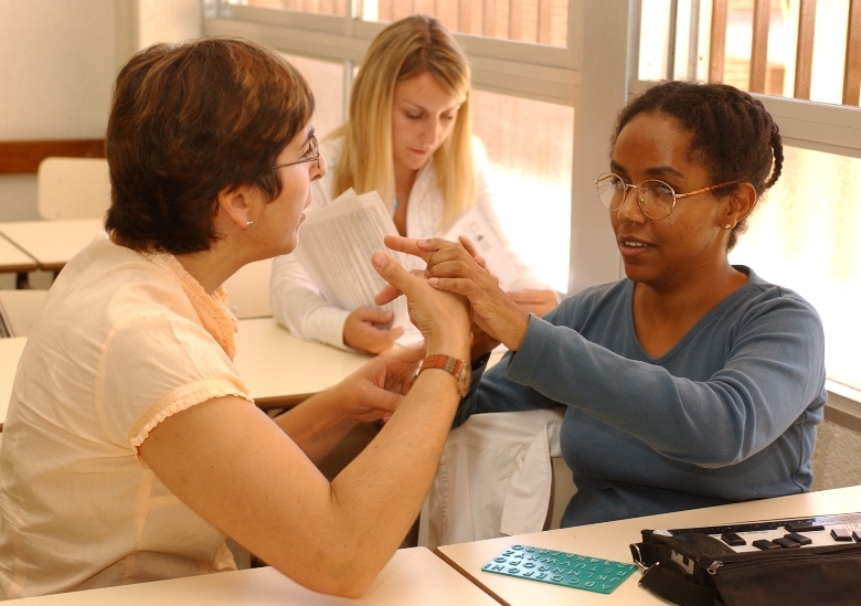 Gennet Corcuera (a la derecha) habla con su medidadora mediante el sistema dactilológico para la comunicación de las personas sordociegas