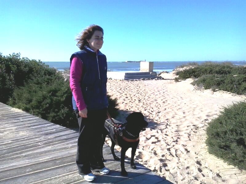 Aina Fernández de paseo por la playa con su perra guía Jamara