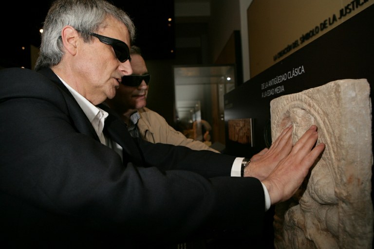 Manuel Sanjuan y José Pedro González (a la derecha) tocando una réplica de un relieve en piedra, en una de las estaciones táctiles del Museo Arqueolólogico