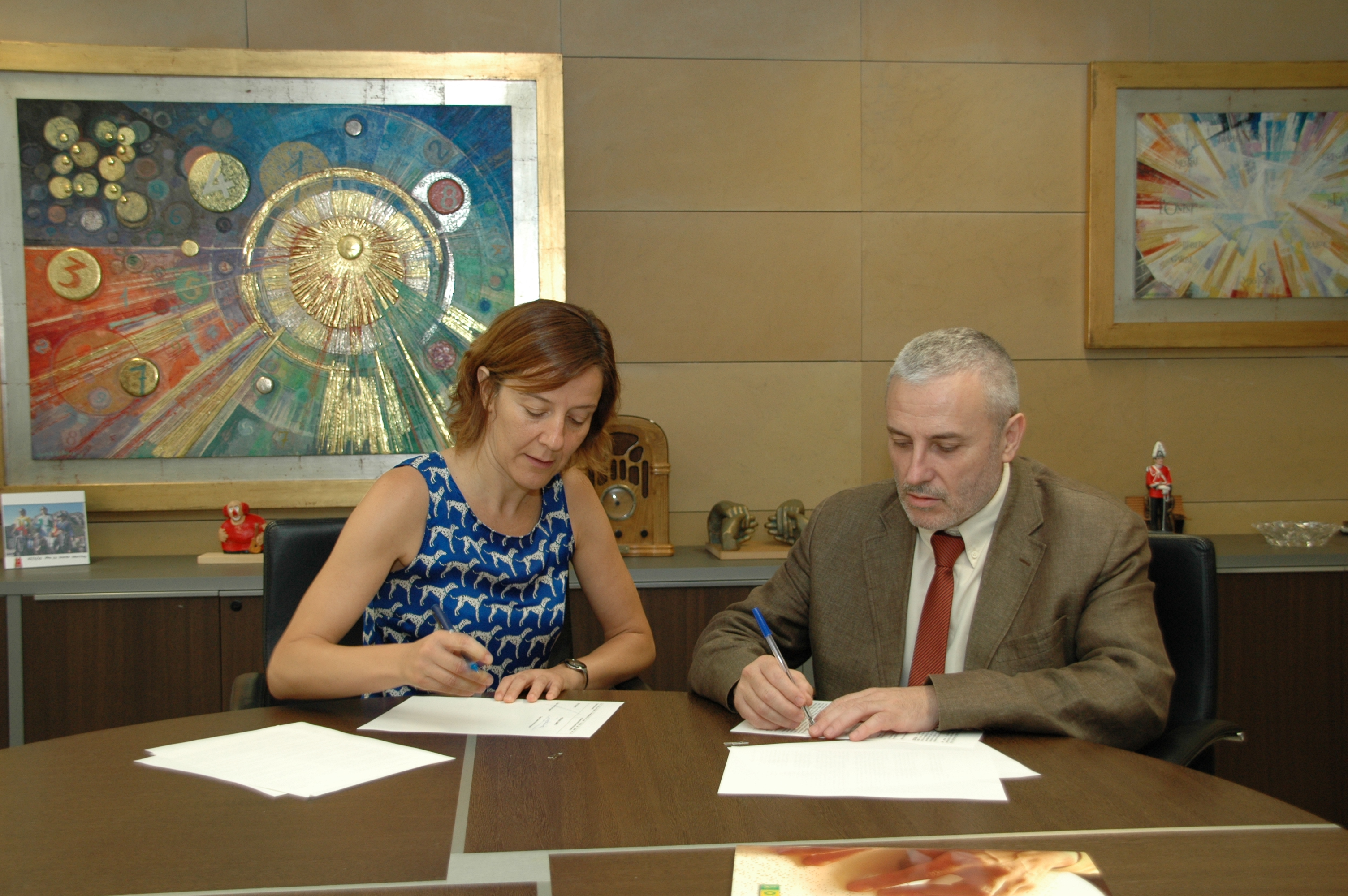 La directora editorial d’Ara Llibres, Izaskun Arretxe, firma junto al delegado territorial de la ONCE en Cataluñaa, Xavier Grau 