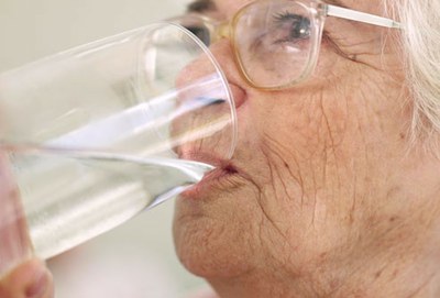 Una anciana bebiendo un vaso de agua