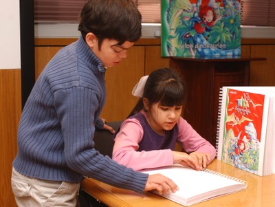Dos niños ciegos, en el aula, manejando material adaptado al braille
