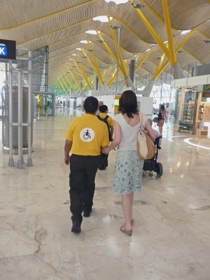 Una persona ciega y otra en silla de ruedas son atendidas por personal de apoyo en un aeropuerto