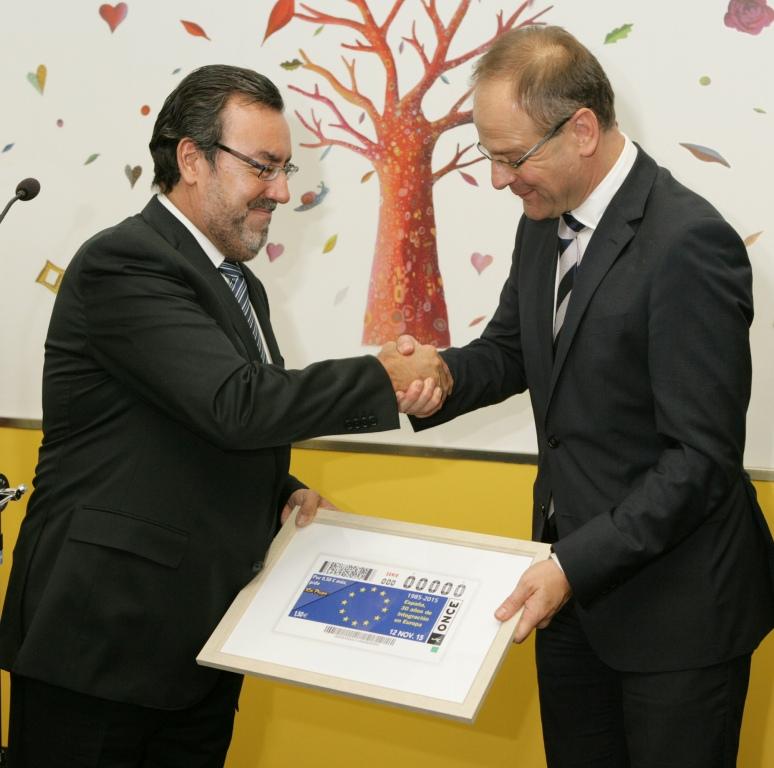 El presidente Carballeda entrega al comisario una reproducción del cupón que la ONCE decidará, el 12 de noviembre, al 30 aniversario de entrada de España en las Comunidades Europeas