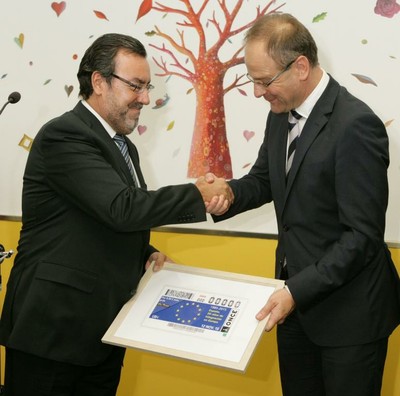 El presidente Carballeda entrega al comisario una reproducción del cupón que la ONCE decidará, el 12 de noviembre, al 30 aniversario de entrada de España en las Comunidades Europeas