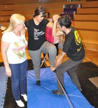 Una de las chicas afiliadas prueba a subir sobre la cuerda de equilibrios apoyada por dos monitores