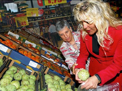 Una voluntaria ayuda a una afiliada a escoger unas frutas en el mercado