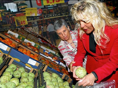 Una voluntaria ayuda a una afiliada a escoger unas frutas en el mercado