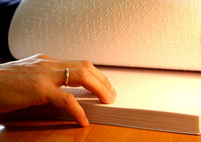 Las manos de una persona ciega leyendo un texto en braille
