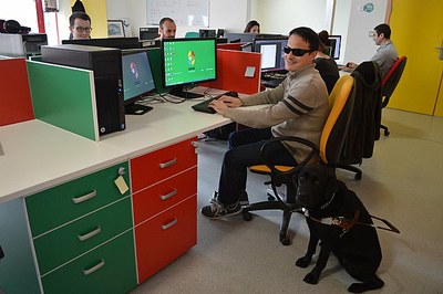 Un estudiante ciego, con su perro guía al lado, en el puesto informático adaptado utilizado para las pruebas piloto por la Politécnica de Cartagena