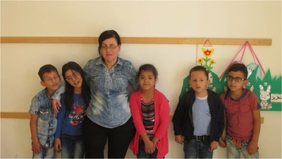 Otro grupo de cinco alumnos, con su instructora, posa junto a algunos de sus trabajos manuales en el aula