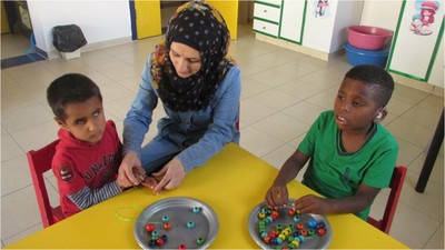 Una maestra enseña a dos niños sordociegos habilidades manuales