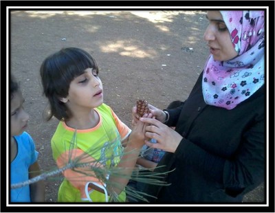 Una maestra palestina muestra a una de sus pequeñas alumnas ciegas a reconocer una piña en pleno bosque