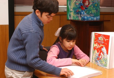 Un niño y una niña afiliados consultan un texto braille en el aula