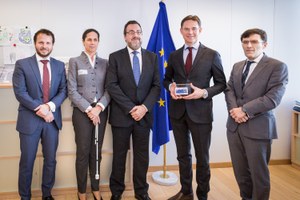 Katanien muestra una reproducción del cupón de la ONCE dedicado a la UE que le entregó nuestra delegación, rodeado por sus visitantes en Bruselas