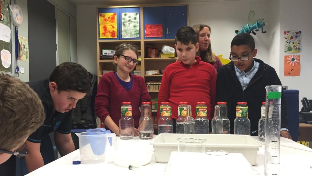 Escolares comprobando la diferente sonoridad al golpear botellas rellenadas con agua a distintos niveles