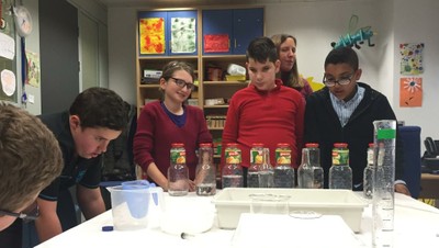 Escolares comprobando la diferente sonoridad al golpear botellas rellenadas con agua a distintos niveles