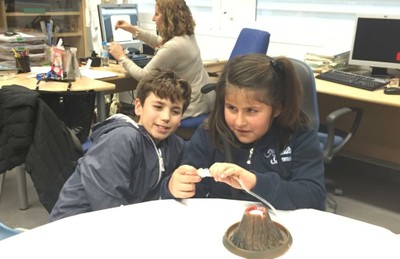 Un niño y una niña afiliados reconstuyendo a escala la actividad de un volcán