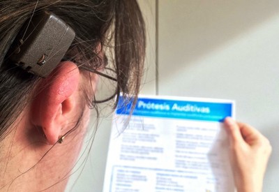 Una joven provista de prótesis auditiva lee la póliza de cobertura de ILUNION