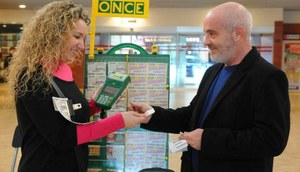 Un comprador adquiere un cupón a una joven vendedora de la ONCE