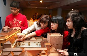 Un grupo de escolares, con su profesora, conociendo al tacto diversos monumentos durante su visita al Museo Tiflológico