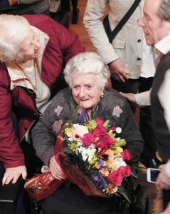 Carmen, en silla de ruedas, es recibida con un ramo de flores a su llegada al acto