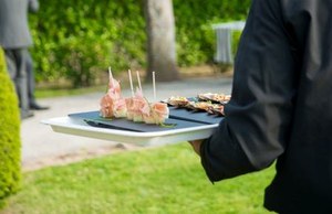 Un camarero sirve unos canapés en un acto público