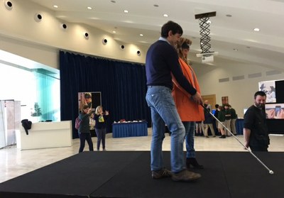 Una visitante es guiada por un técnico de la ONCE para moverse a ciegas con un bastón por el circuito de movilidad