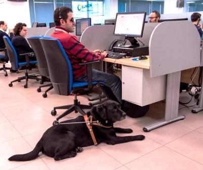 Un operario ciego, con su perro guía, trabajando en las instalaciones del Contact Center de ILUNION