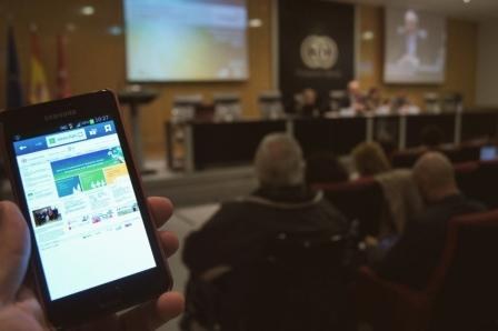 Una persona ciega utiliza en su móvil una aplicación accesible, en el transcurso de un acto público