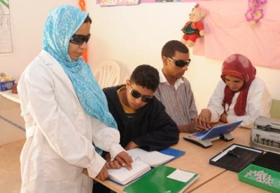 Dos profesoras de los campamento enseñan a otros tantos alumnos lectura braille y manejo del ordenador