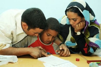 Un profesor y una profesora saharauis enseñan a un niño ciego rudimentos de lectura braille