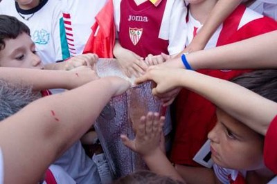 Media docena de pequeños afiliados rodean y reconocen con sus manos la Copa europea