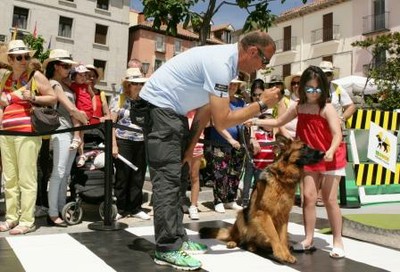 Un instructor de la ONCE muestra a una niña como manejarse con un perro guía en la plaza de El Escorial 
