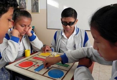Escolares latinoamericanos (uno de ellos ciego) practican con un juego de mesa adaptado, aportado por la ONCE