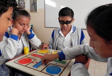 Escolares latinoamericanos (uno de ellos ciego) practican con un juego de mesa adaptado, aportado por la ONCE