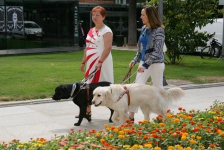Dos usuarias pasean con sus respectivos perros guía en las inmediaciones de la exposición