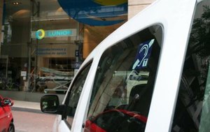 Un vehículo, aparacado frente a un establecimiento de ILUNION, con el logotipo de instalación de bucle magnético
