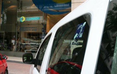 Un vehículo, aparacado frente a un establecimiento de ILUNION, con el logotipo de instalación de bucle magnético