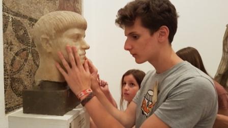 Otro escolar toca una cabeza esculpida en el Museo