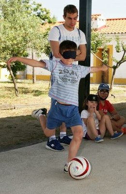 Uno de los chavales (provisto de antifaz) intenta chutar en una práctica de fútbol a ciegas