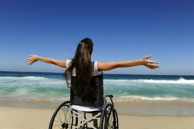 Joven en silla de ruedas en una playa frente al mar