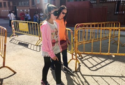 Una estudiante con antifaz y bastón blanco realizando un circuito de movilidad 