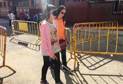 Una estudiante con antifaz y bastón blanco realizando un circuito de movilidad 