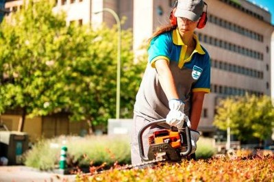 Una operaria de jardinería de ILUNION trabajando con una podadora