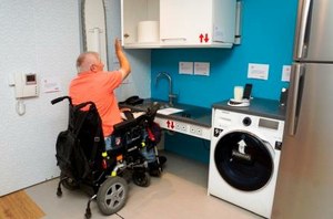 Una persona en silla de ruedas comprueba la accesibilidad de la cocina de la casa accesible