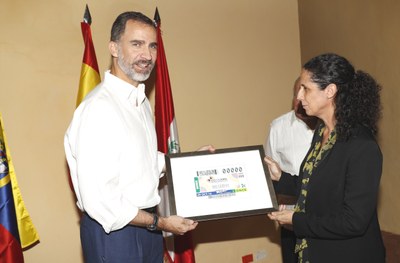 La consejera general Ana Peláez hace entrega a Felipe VI de la reproducción del cupón enmarcada durante su estancia en Cartagena de Indias