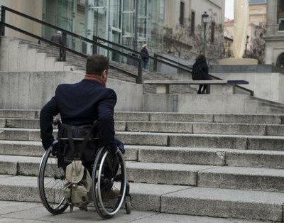 Persona en silla de ruedas frente a una escalinata