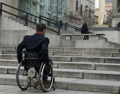 Persona en silla de ruedas frente a una escalinata